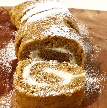 Sliced pumpkin roll on wooden cutting board