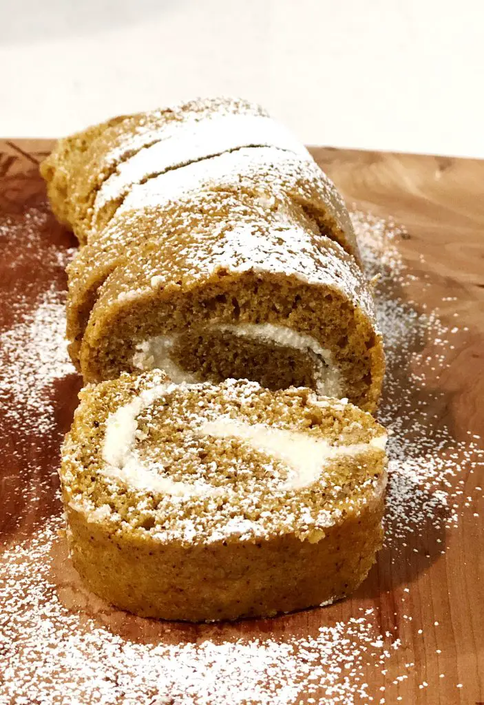 Sliced pumpkin roll on wooden cutting board 