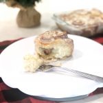 Perfect Christmas cinnamon roll on white plate with fork