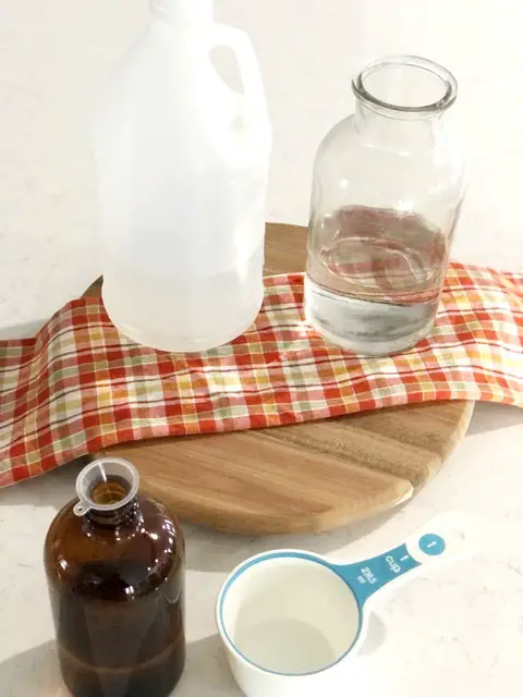 vinegar bottle, glass jar with water, measuring cup and amber glass bottle
