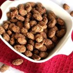 white bowl filled with cinnamon sugar almonds on red towel