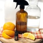 Amber spray bottle on wooden board with orange slices and orange essential oil