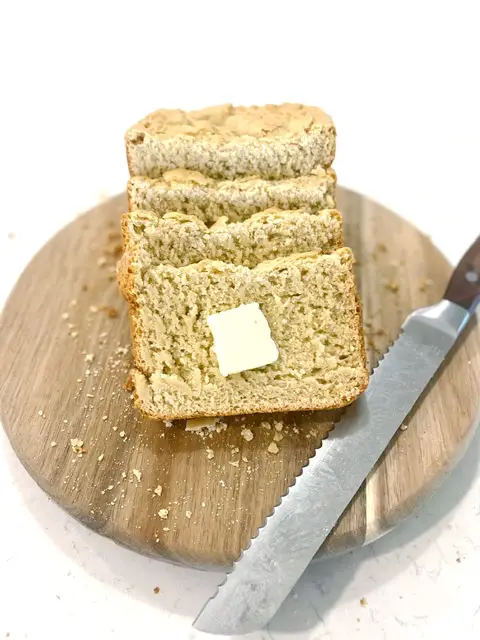 sliced gluten free bread on cutting board with bread knife 