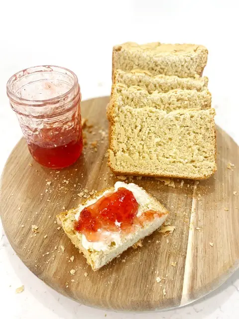 sliced gluten free bread on wooden cutting board with strawberry jam