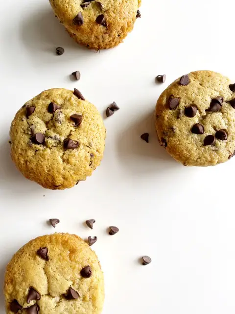 gluten free dairy free chocolate chip banana muffins on white counter with chocolate chips