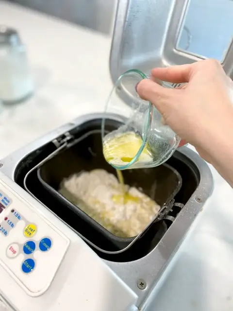 hand pouring melted butter into bread machine