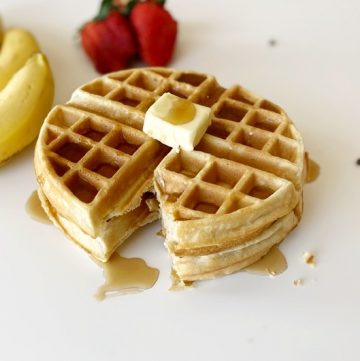stacked gluten free waffles topped with butter and syrup