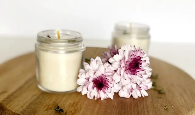 Two organic beeswax candles on a wooden cutting board with purple flowers