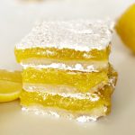 3 gluten free lemon bars stacked on top of each other with lemon slices