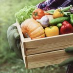 woman holding crate of vegetables