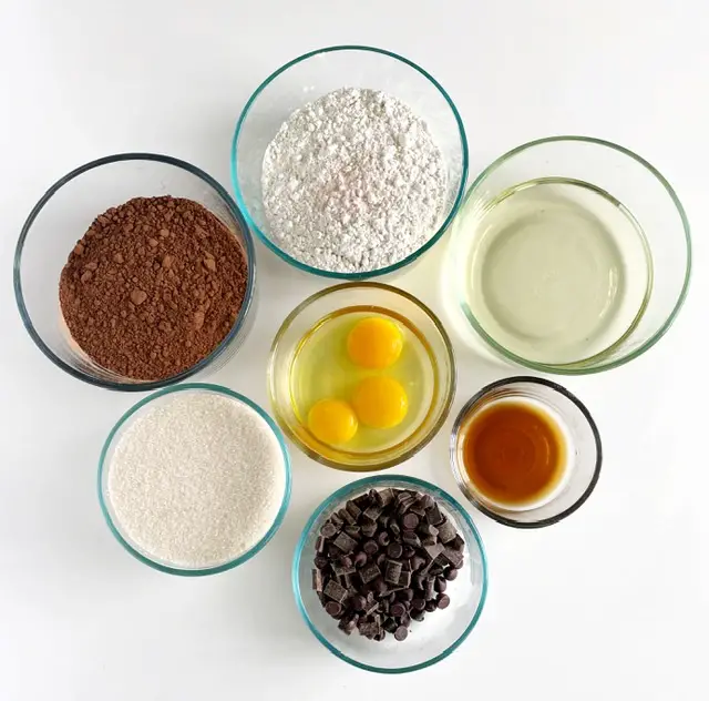 Ingredients for gluten free fudge brownies in glass bowls on white table 