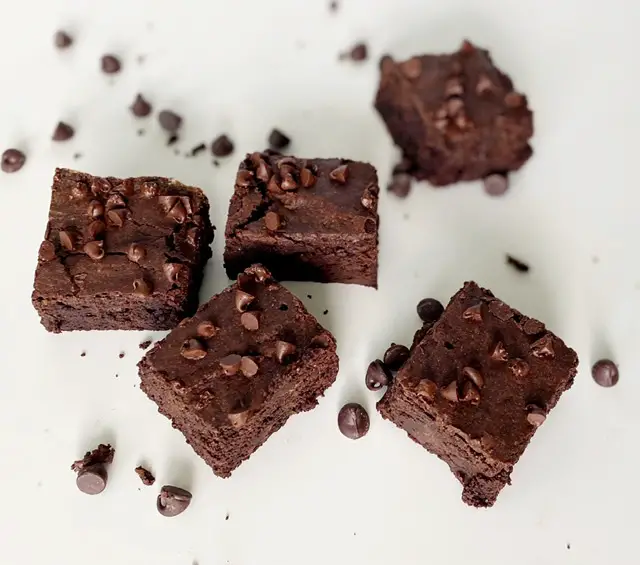 5 gluten free fudge brownies on white table with chocolate chips 