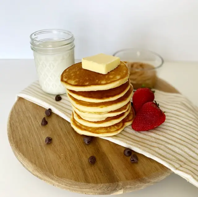 stack of easy and fluffy gluten free pancakes with butter, glass of milk and strawberries 