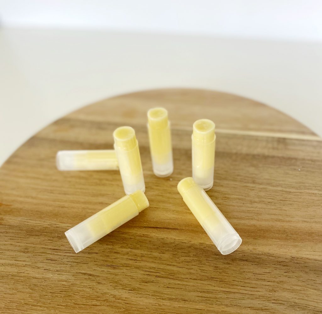6 tubes of homemade beeswax lip balm on butcher block