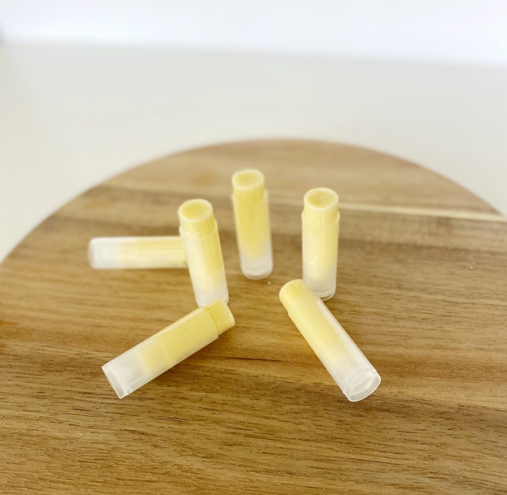 6 tubes of homemade beeswax lip balm on butcher block 